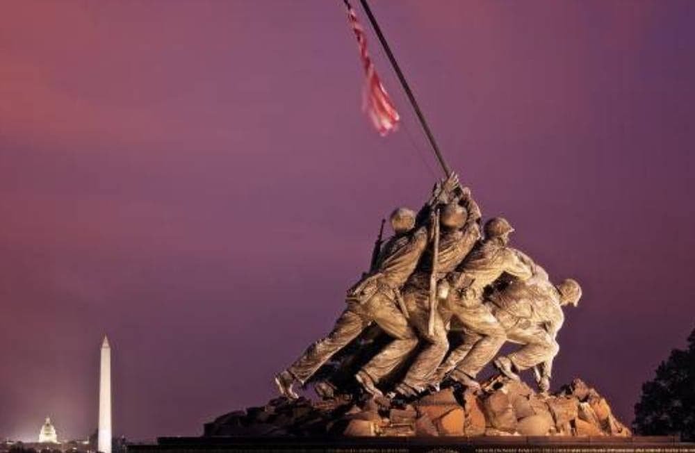 The Marine Corps War Memorial at dusk, with the Washington Monument and the Capitol in the distance.